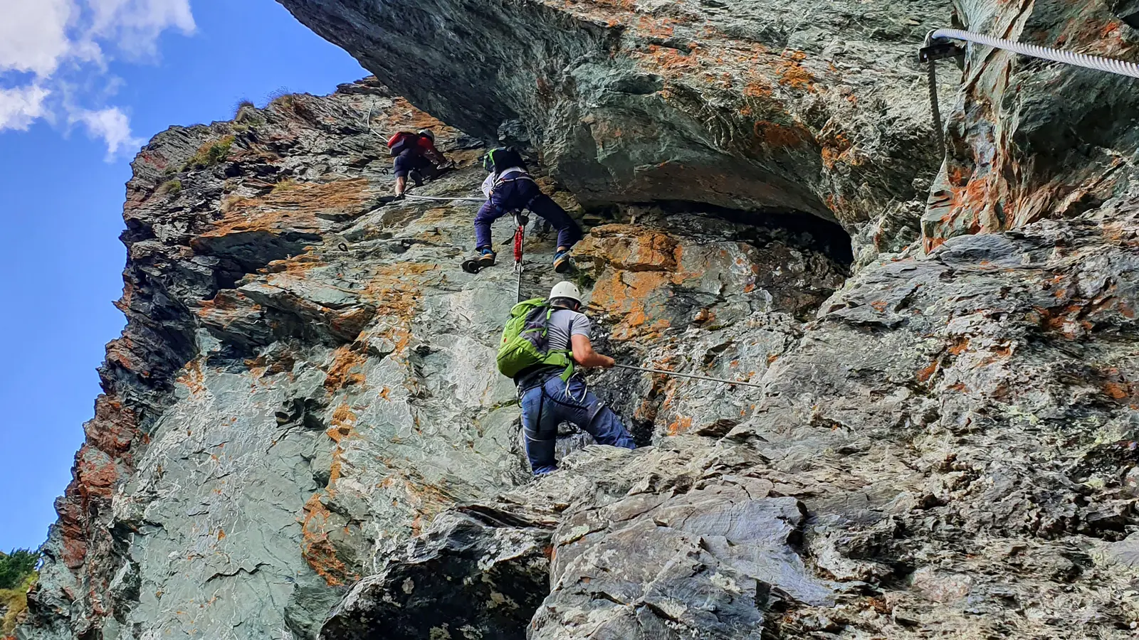 Klettersteiggeher mit Helm und Klettersteigset an einer drahtseilversicherten Felswand am Via-Ferrata-Falkert in den Nockbergen, Kärnten