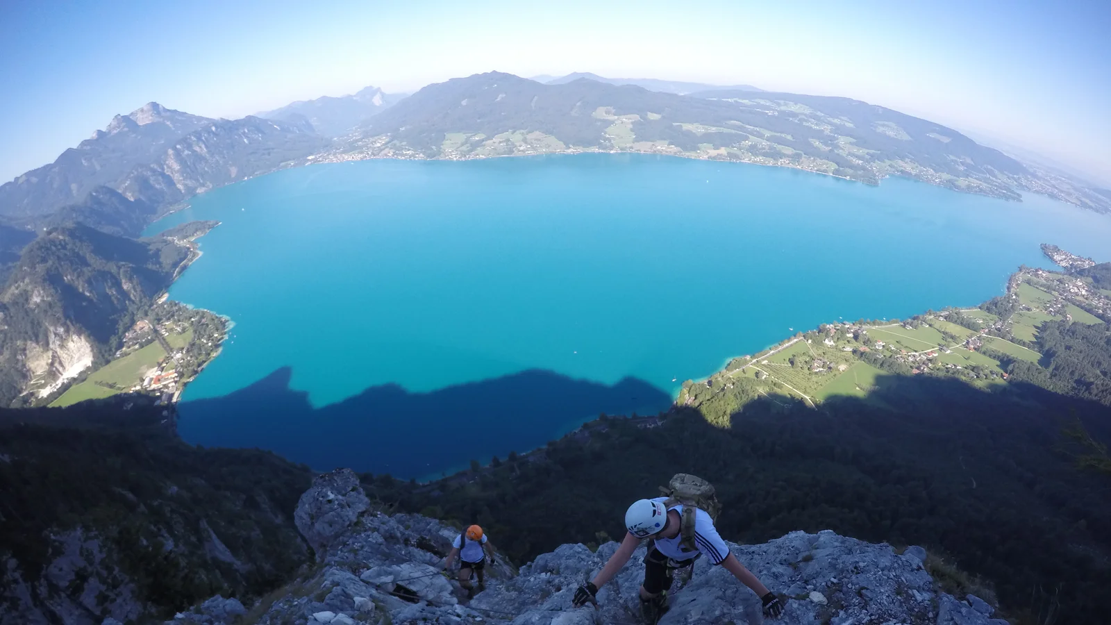 Kletterer im Mahdlgupf-Klettersteig kurz vor dem Ausstieg, senkrecht darunter der türkise Attersee